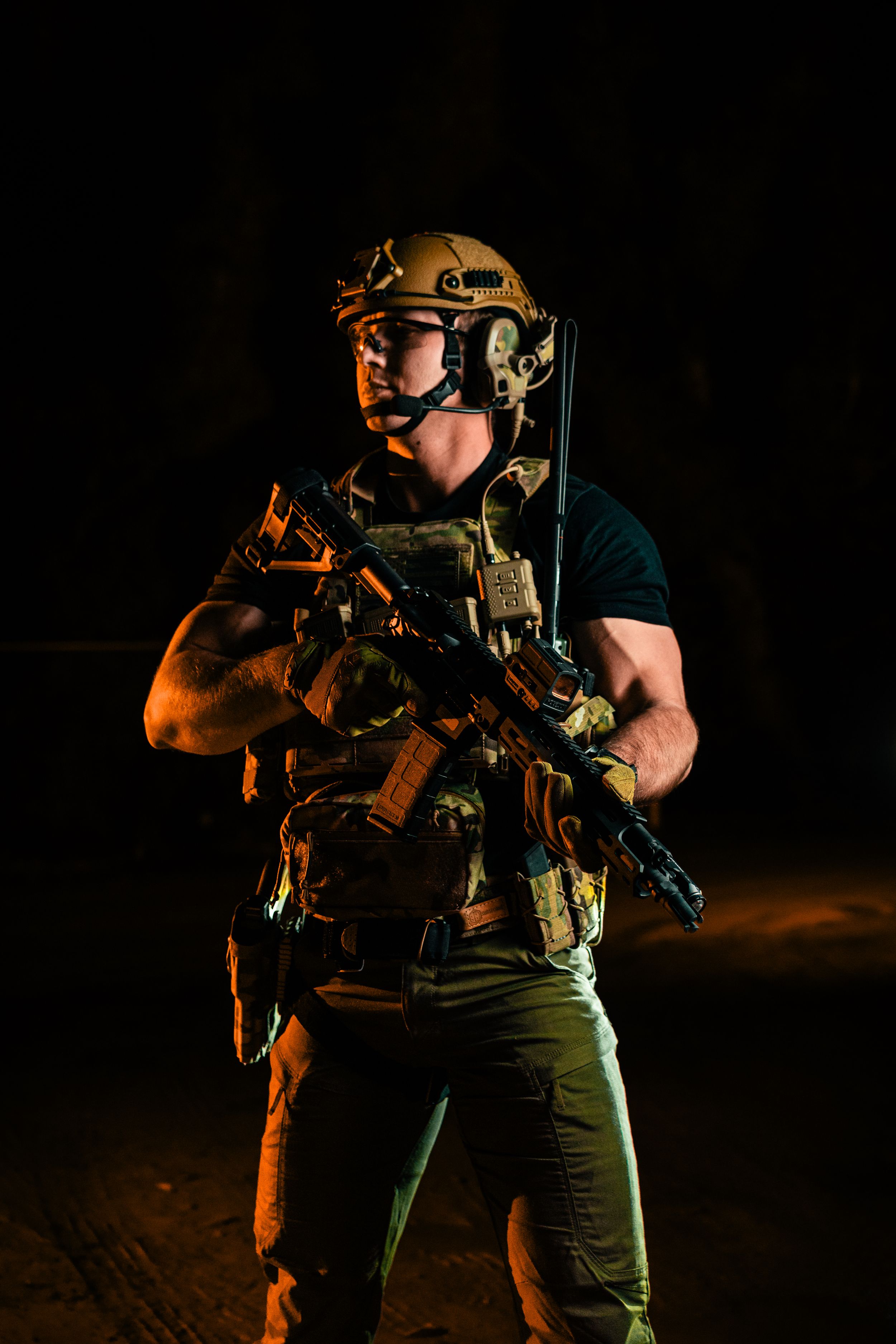 Combat-equipped operator with tactical helmet and rifle in dramatic lighting.