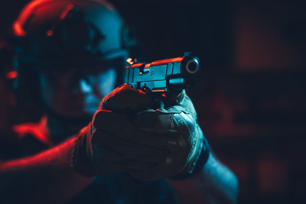 Close-up of rifle scope and barrel with dramatic red and blue lighting.