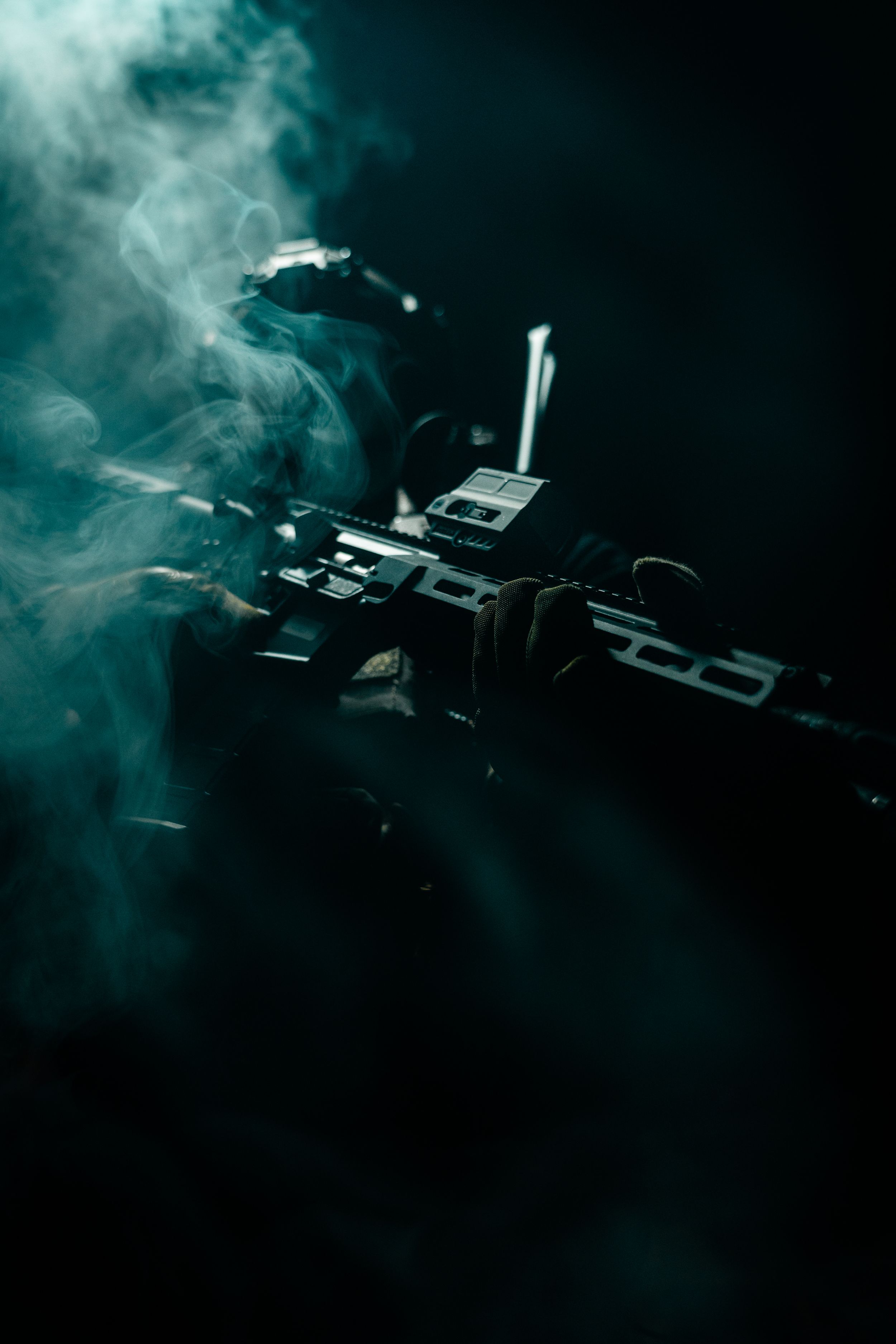 Atmospheric shot of firearm silhouette with smoke effects in dark setting.