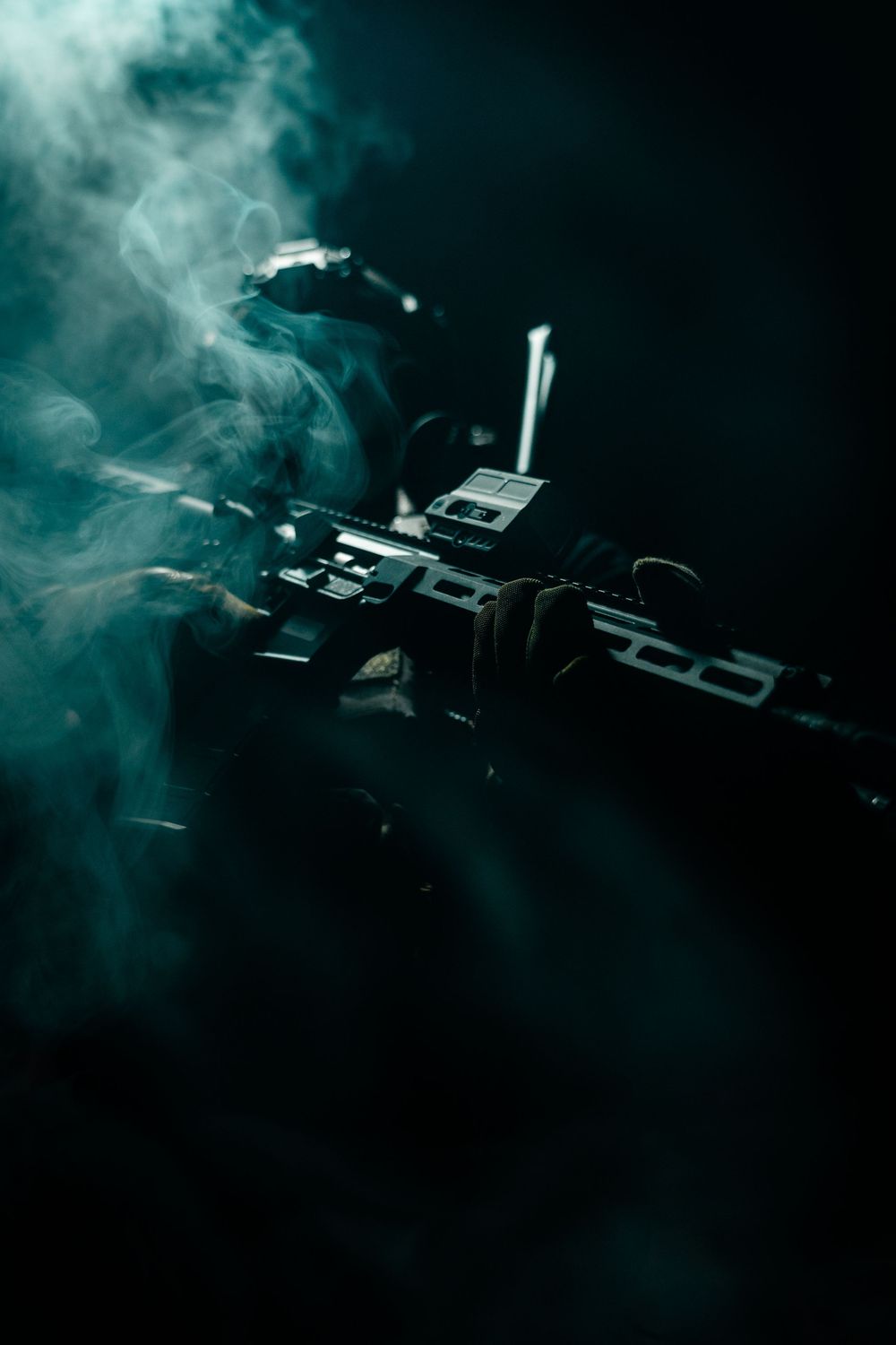 Atmospheric shot of firearm silhouette with smoke effects in dark setting.