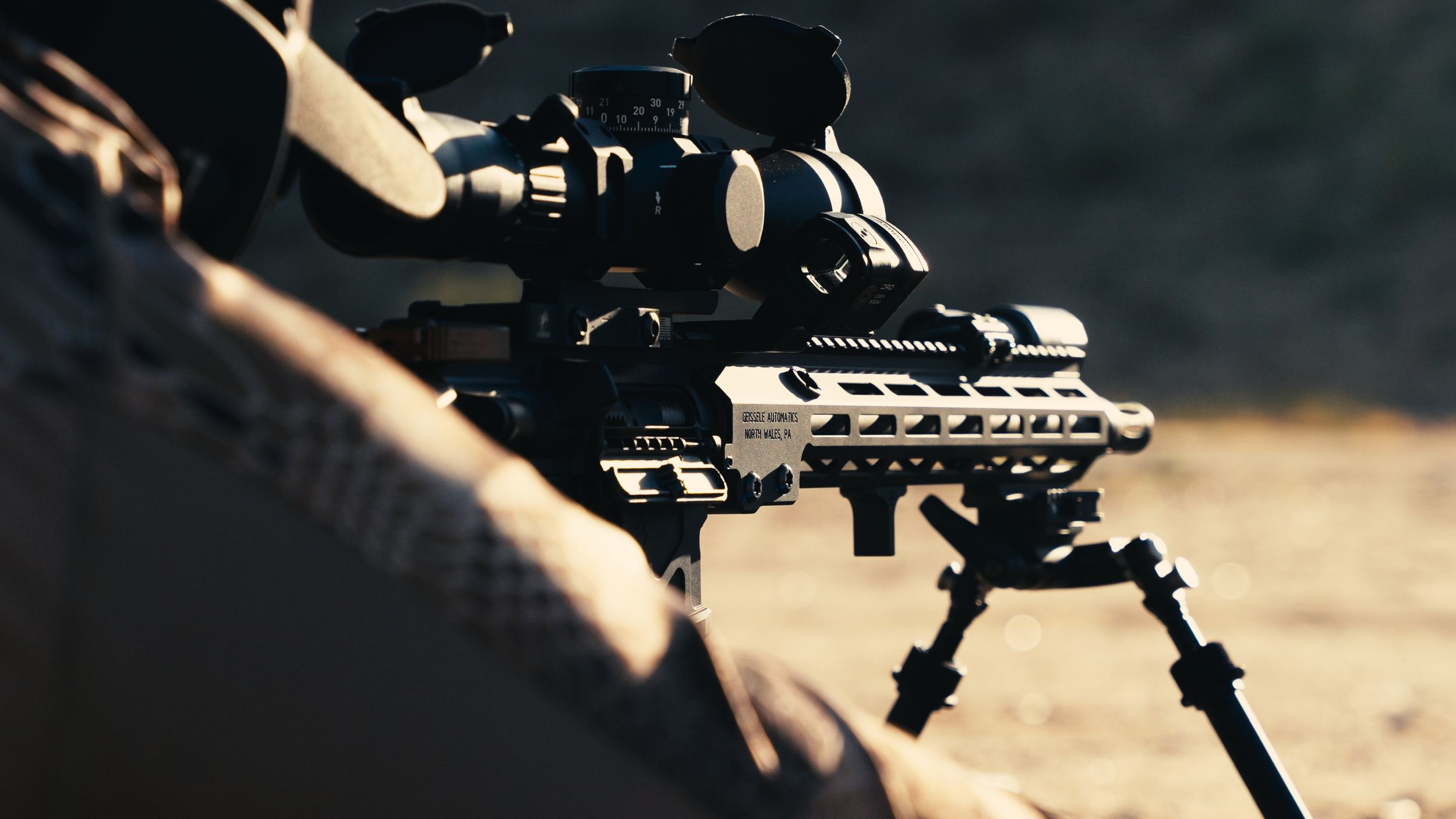Tactical rifle with mounted scope and accessories on a dark background.