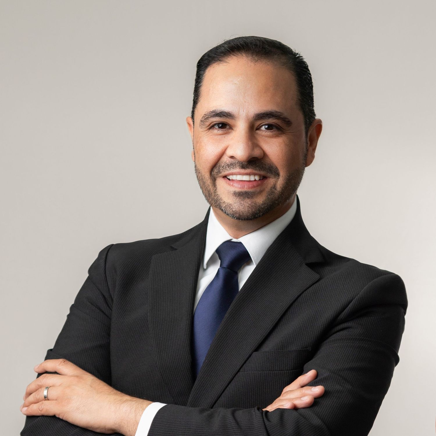 Professional headshot series of someone in a dark suit and blue tie against a light gray background.
