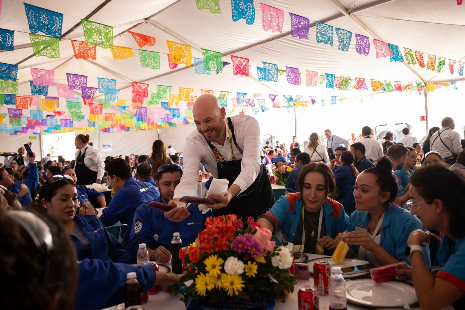 Festive dining hall decorated with vibrant Mexican papel picado banners strung across ceiling during celebration.