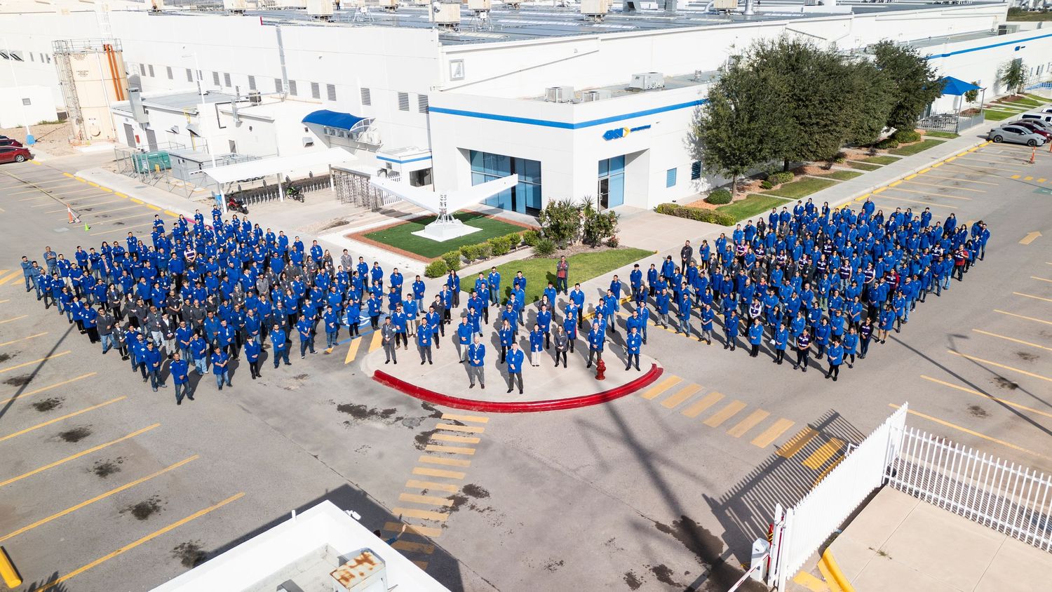 Aerial view of employees in blue uniforms forming a large human pattern in a parking lot.
