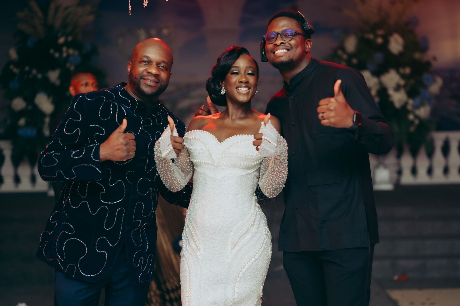 A wedding celebration with people smiling and giving thumbs up gestures in formal attire.