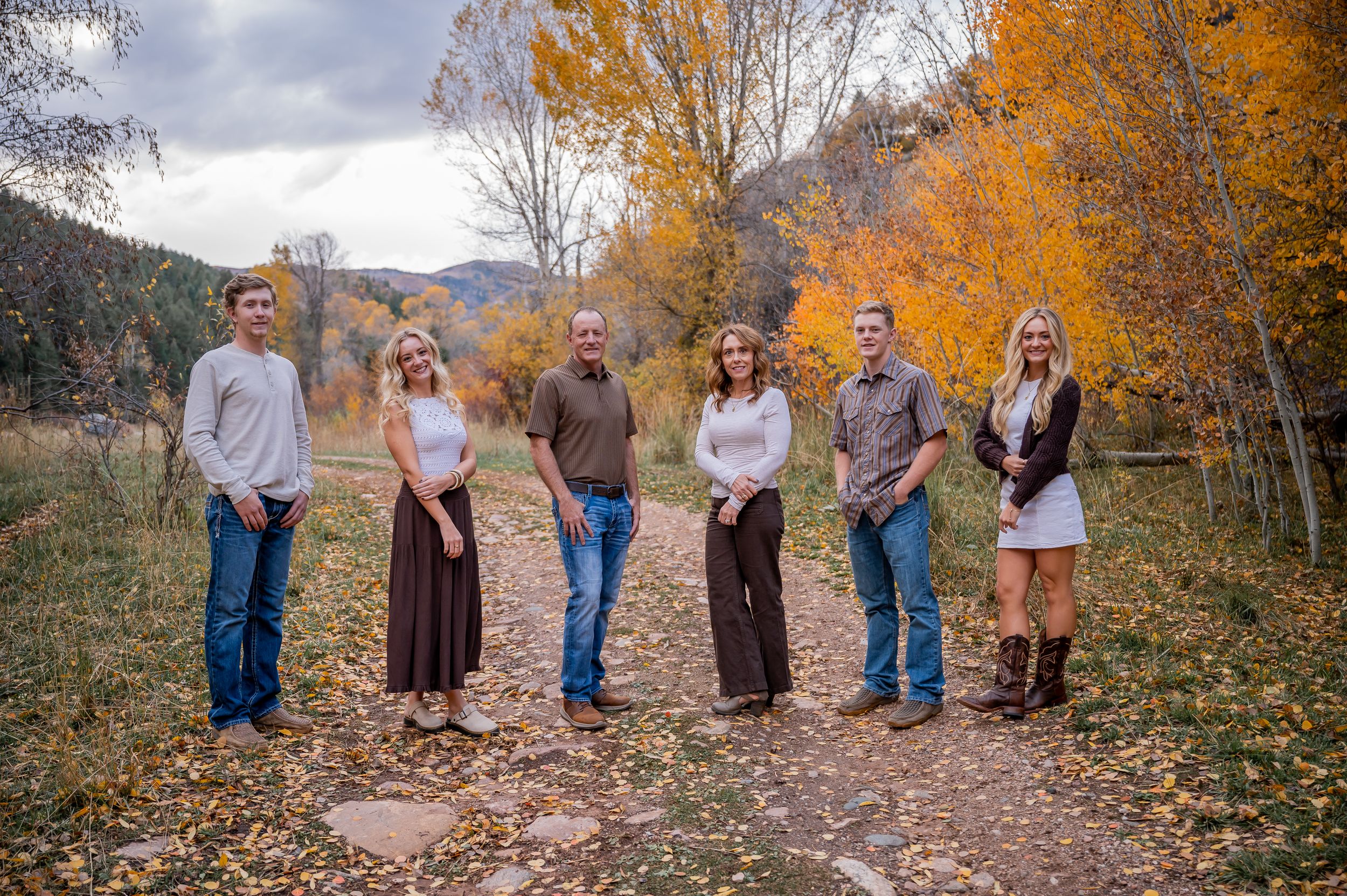 A group stands on an autumn path surrounded by golden aspen trees and mountain views.