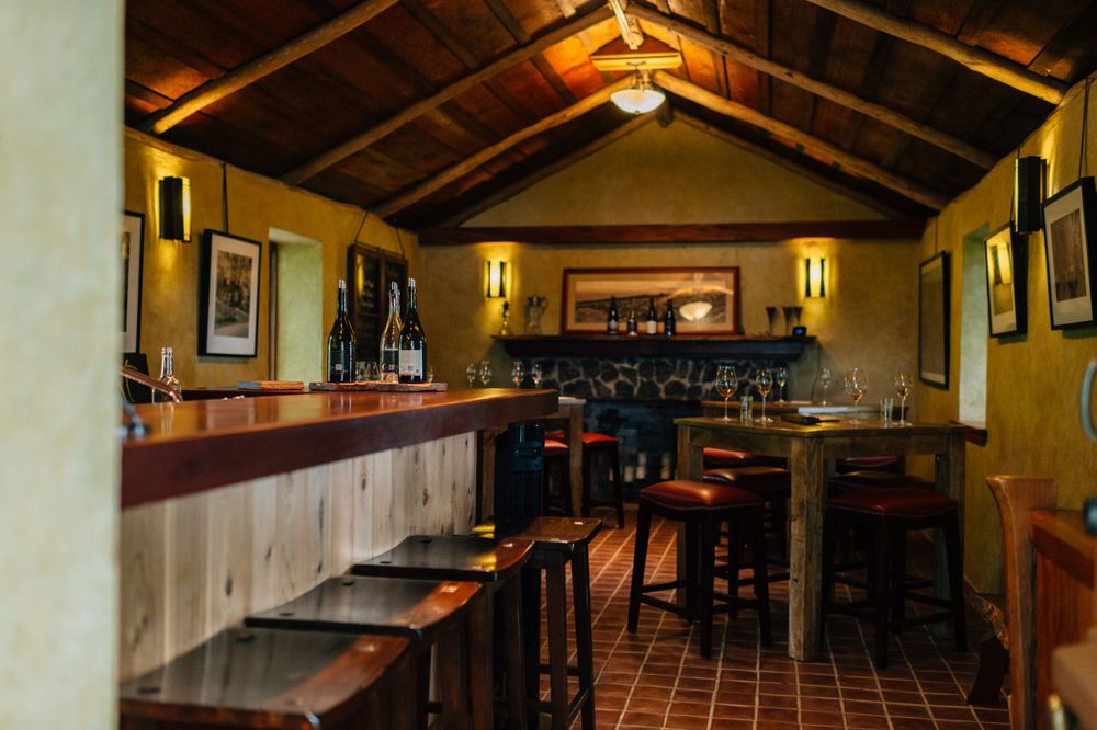 Rustic interior of a wine tasting room with exposed wooden beams and warm lighting.