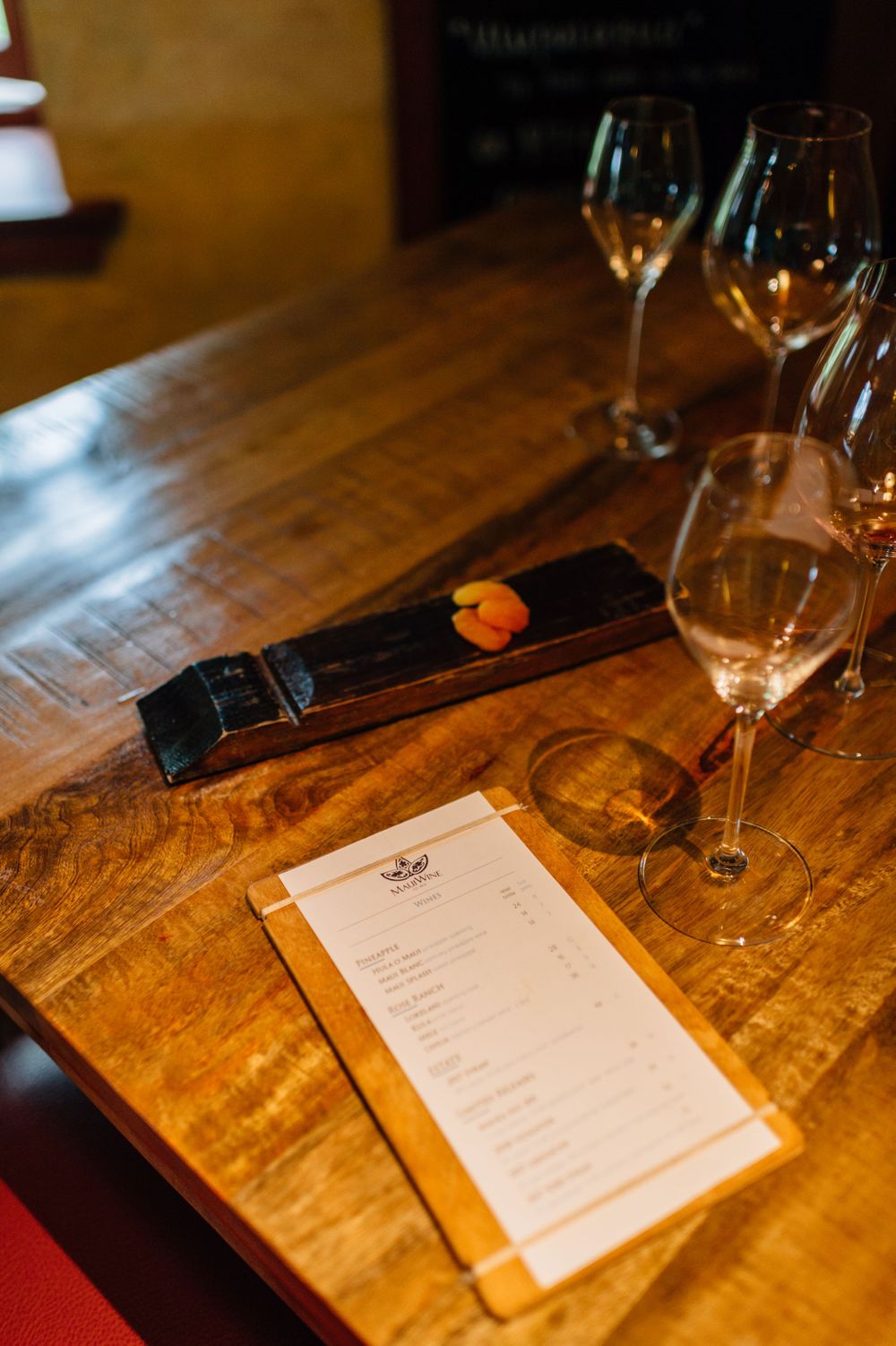 Wine tasting menu and glasses set on a weathered wooden table.