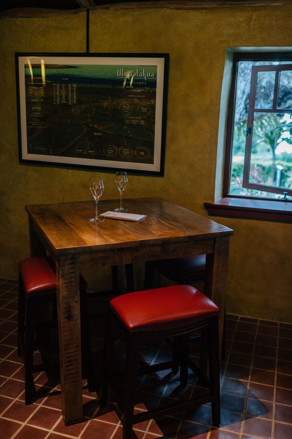 Intimate dining area with wooden tables and red leather seating against yellow walls.