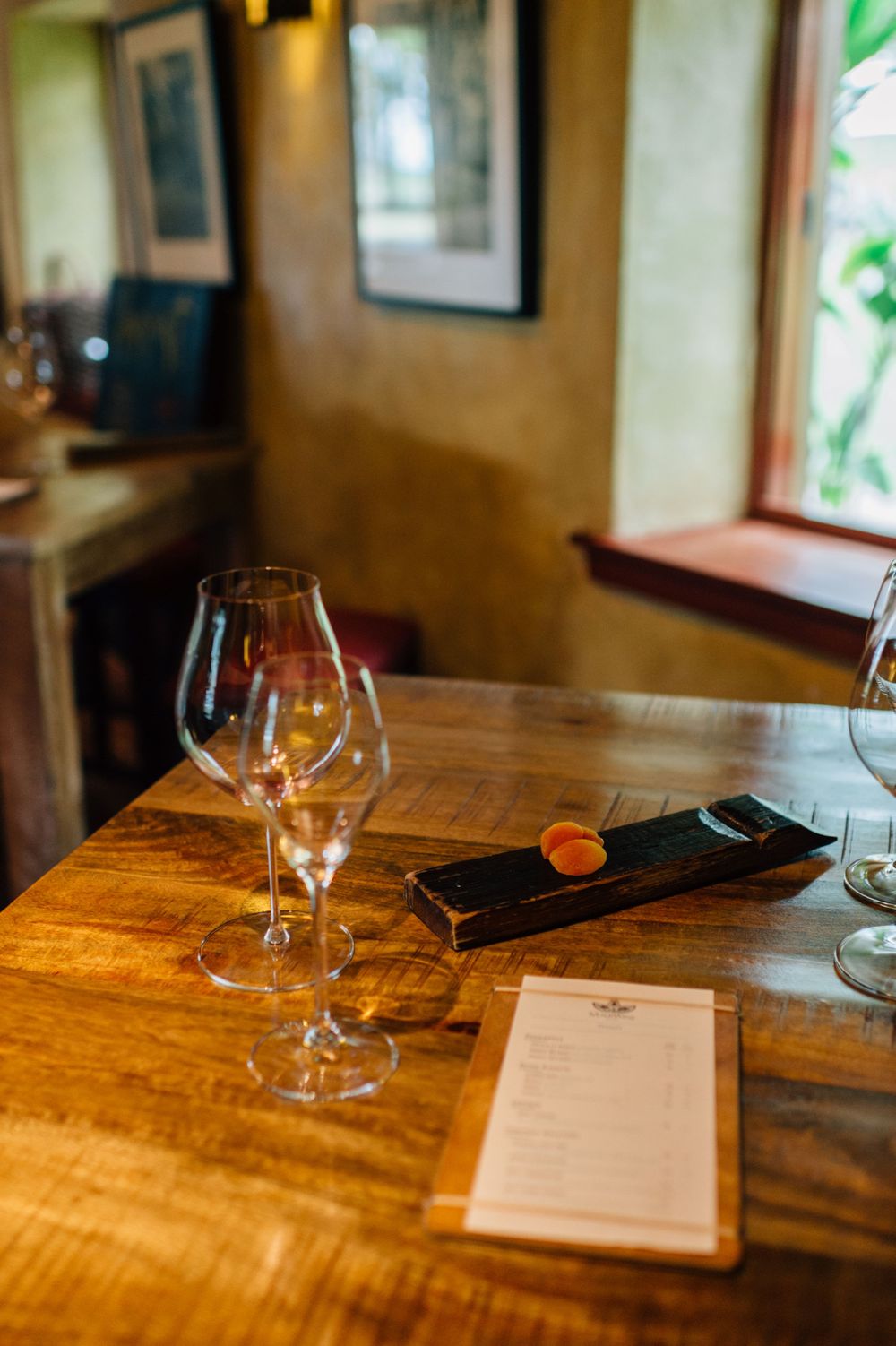 Table setting with wine glasses and menu in natural daylight.