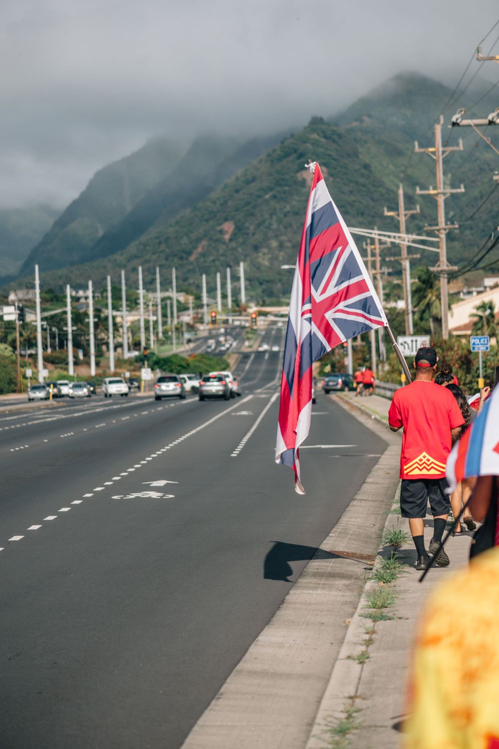 Hawaiian flags wave along a highway with misty mountains in the background.