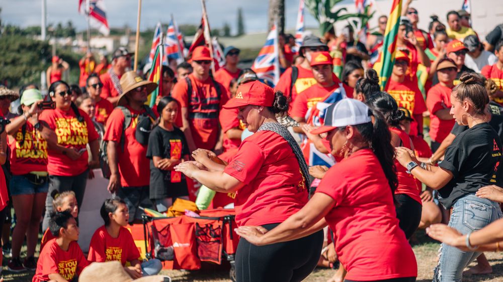 Crowd dressed in red shirts gathers outdoors for a community event.