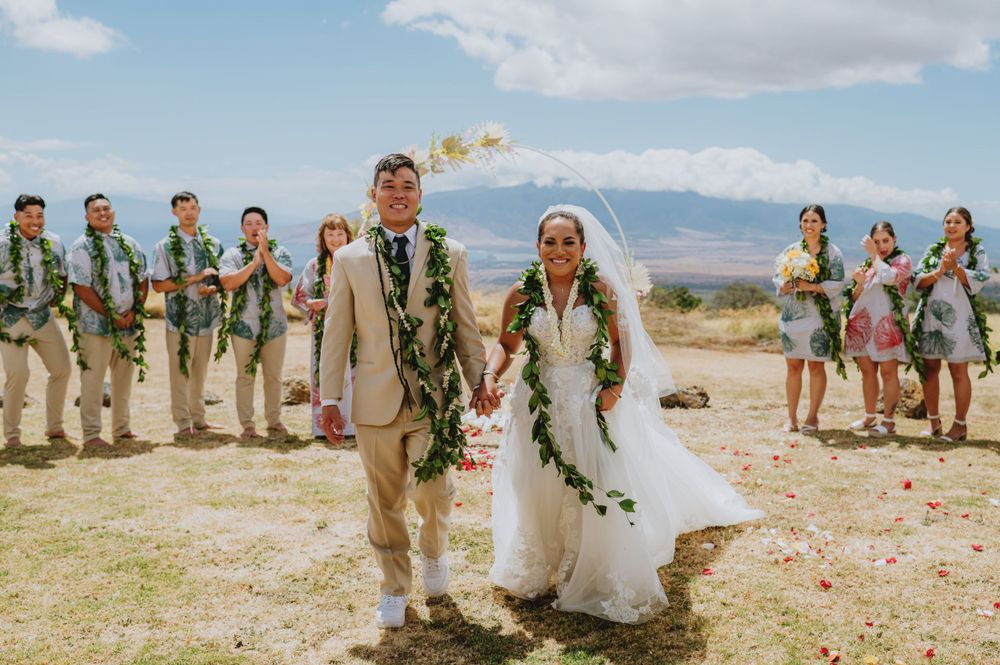 Wedding party and guests gathered on desert terrain with mountain views.