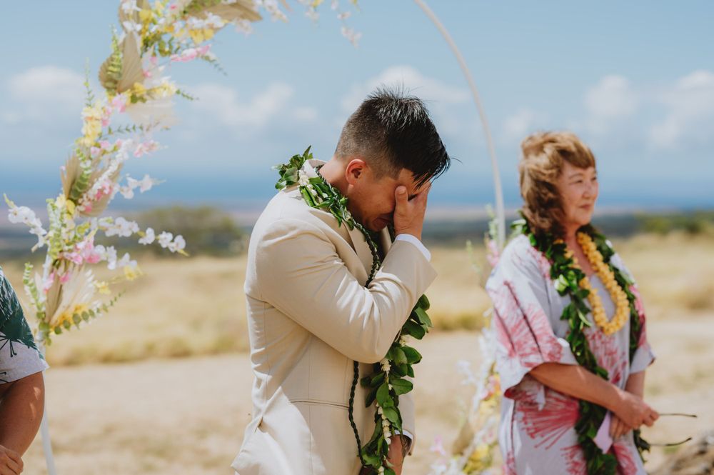 Outdoor wedding ceremony with floral decorations against mountain backdrop.