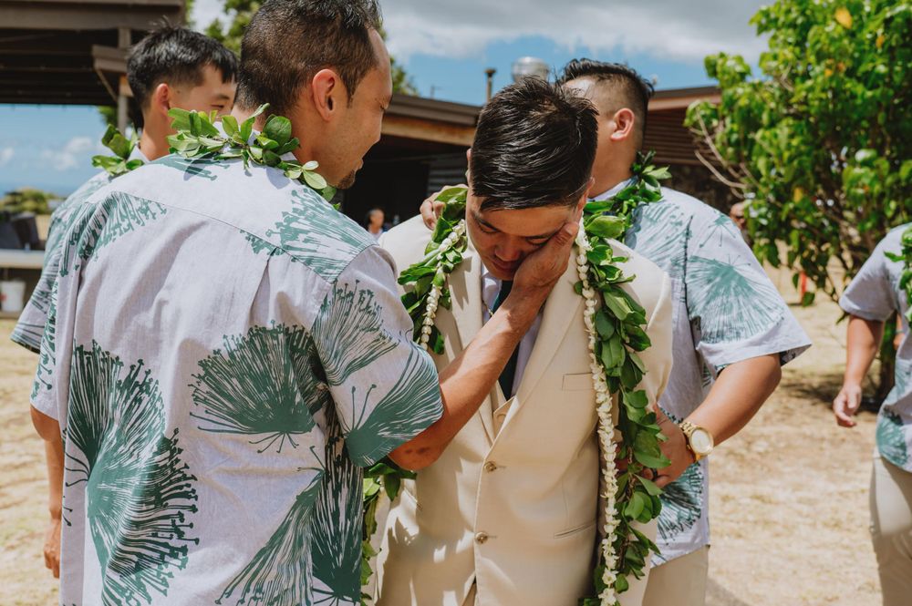 Wedding party members in tropical print attire under covered outdoor venue.