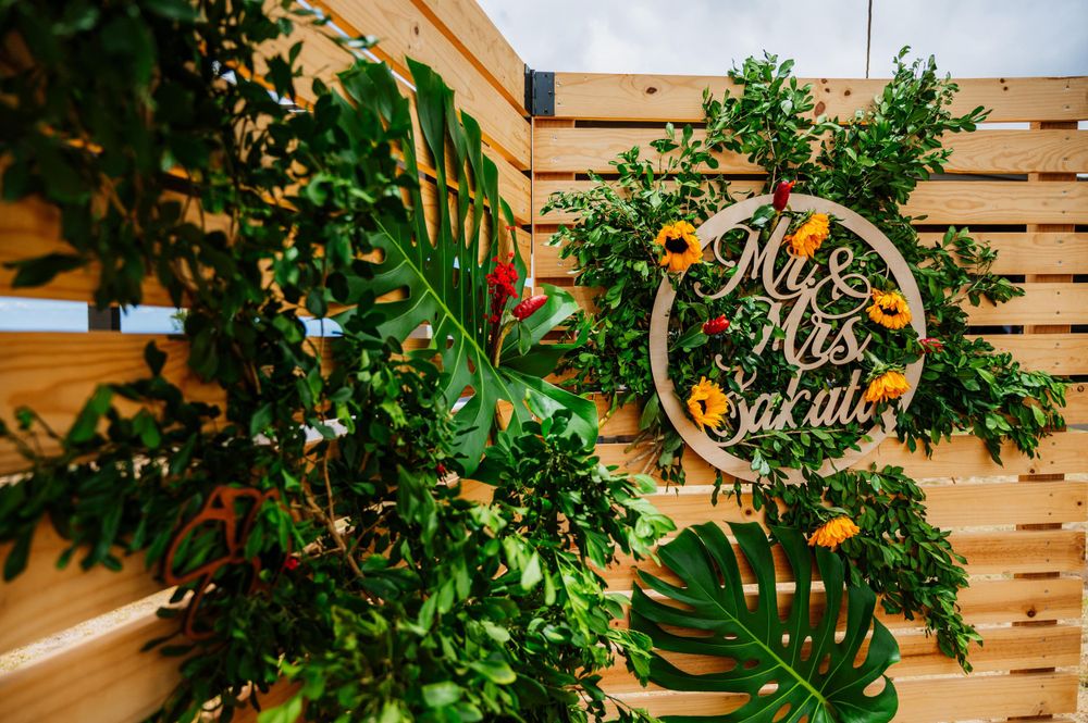 Wedding decor featuring greenery and wooden signage against natural wood paneling.