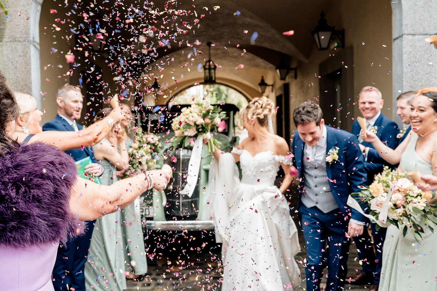 Wedding guests shower newlyweds with confetti outside a church after their ceremony celebration.