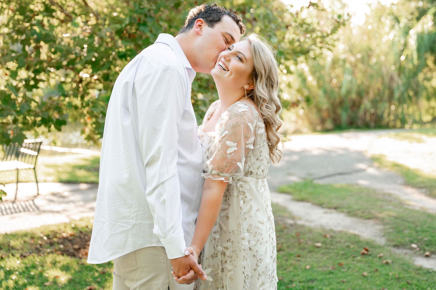 A couple embraces during their engagement photoshoot in a park setting.