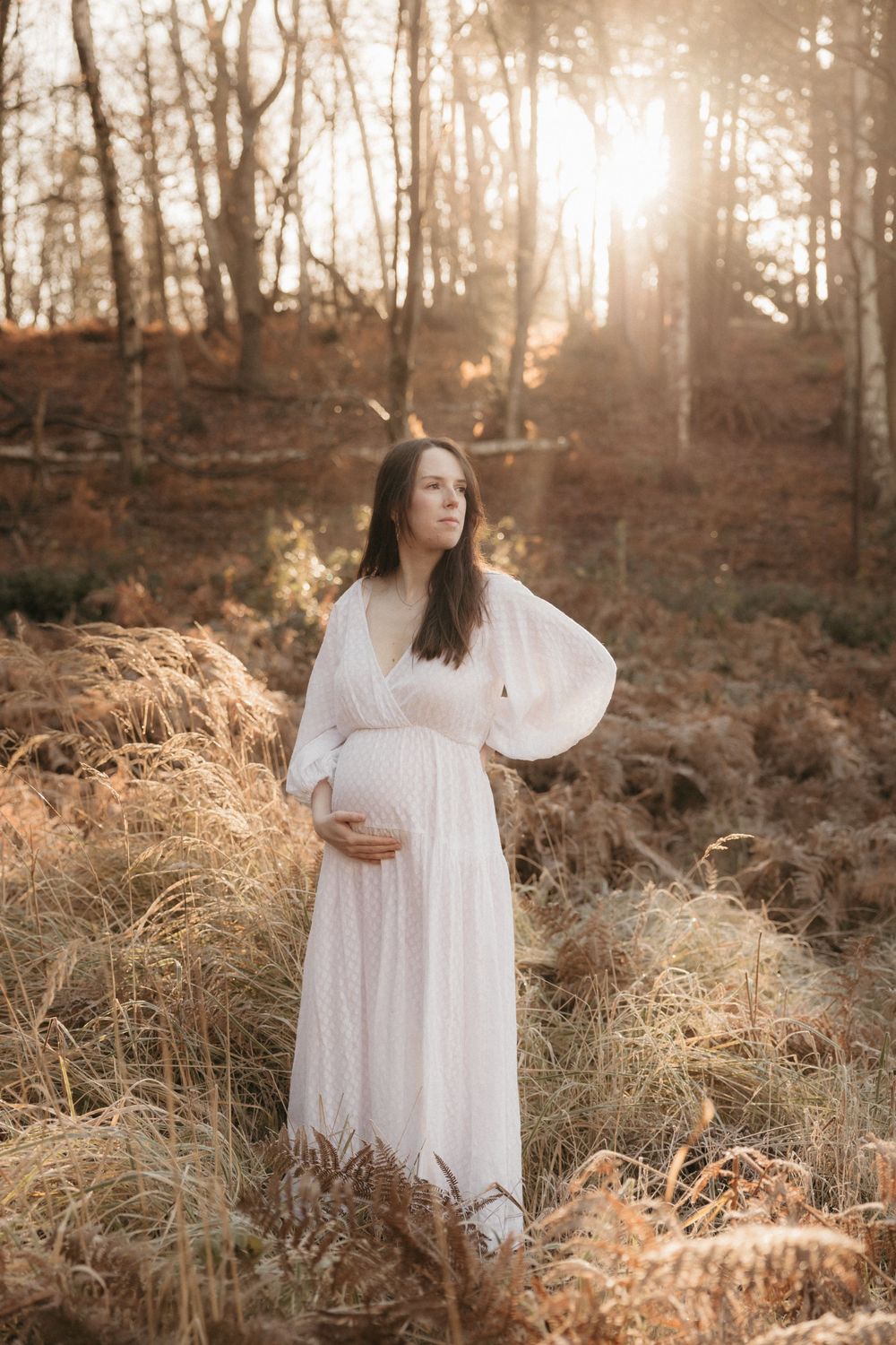 Ethereal forest scene with flowing white dress against autumn foliage and streaming sunlight.