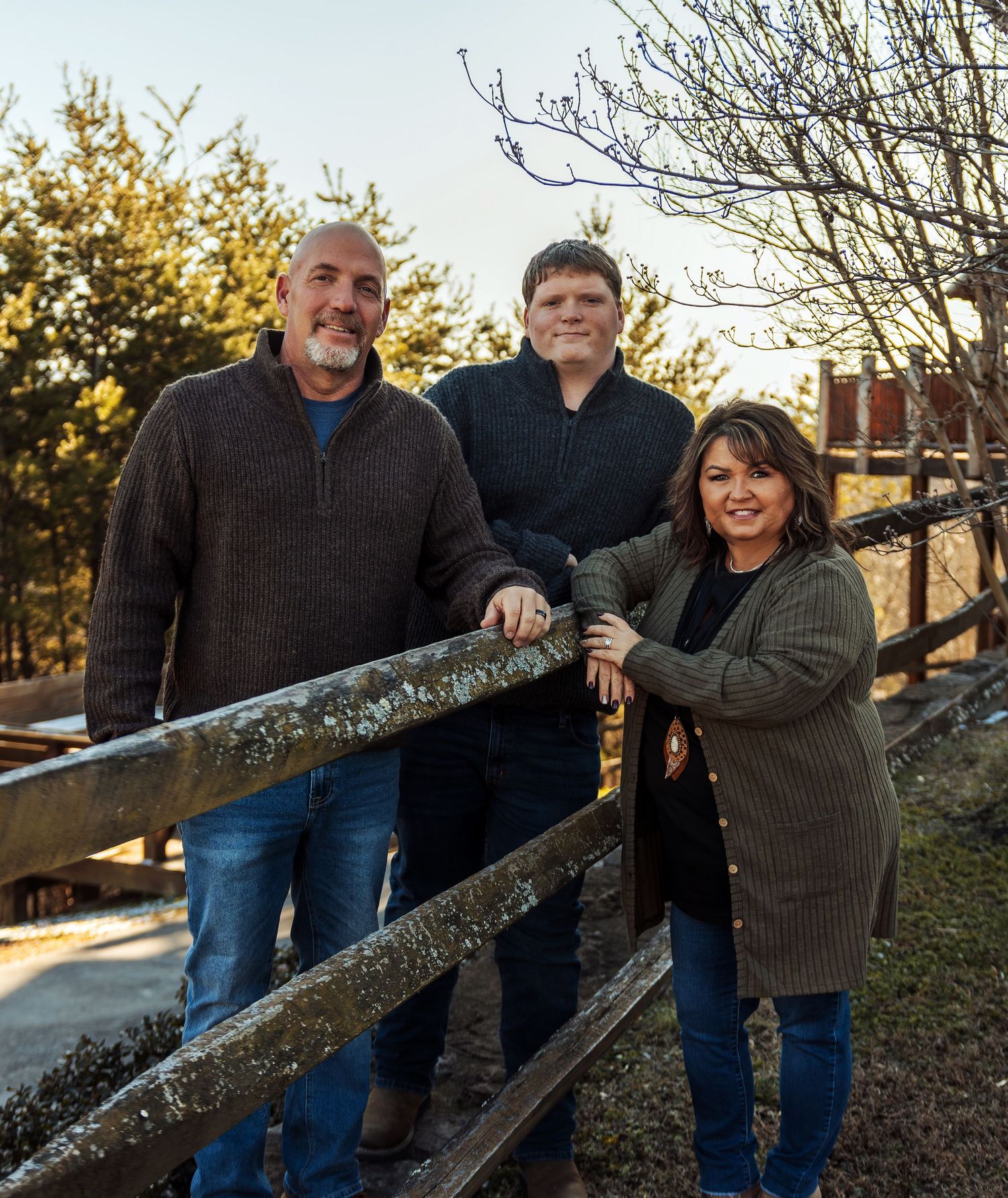 A group stands together by a wooden fence at sunset during an outdoor photo session.