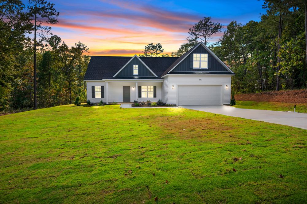 Beautiful sunset view of a modern residential home with pine trees and well-maintained lawn in a peaceful setting.