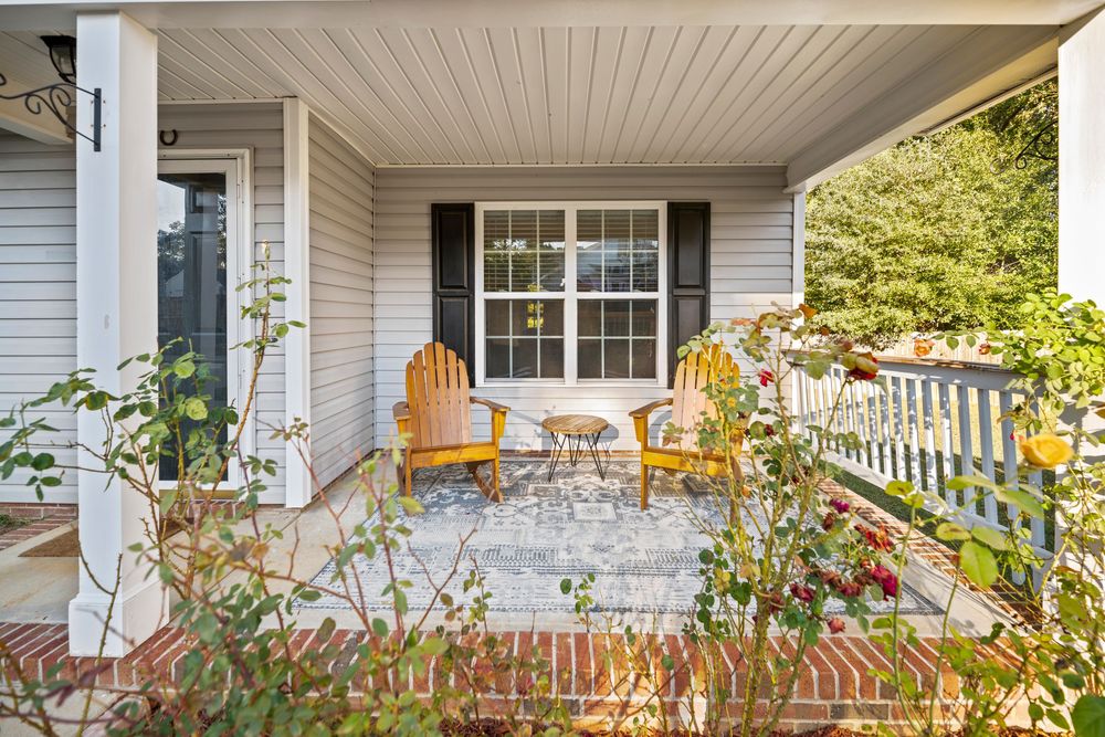 A charming white porch with beadboard ceiling and decorative railing features colorful hanging flower baskets in summer.
