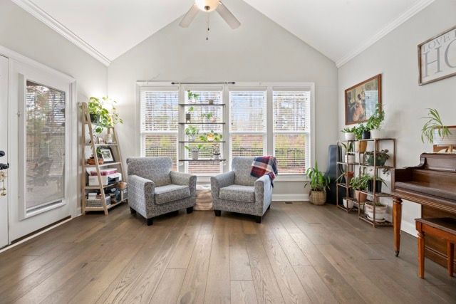 Bright interior listing photo of a living space with hardwood floors, fireplace, and large windows in Sanford NC