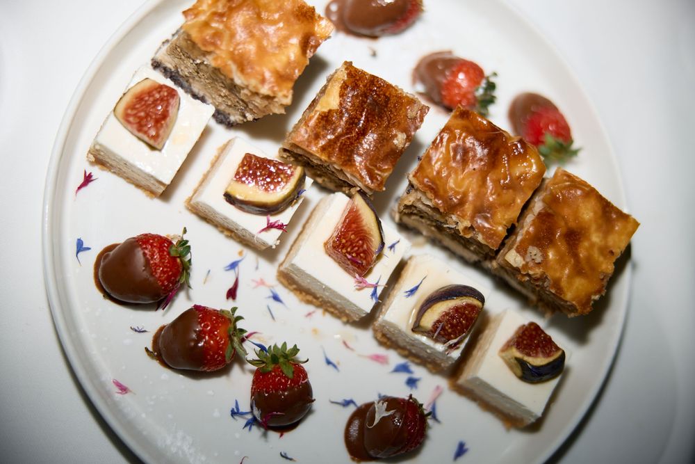 Elegant dessert plate with chocolate covered strawberries and pastry squares arranged artistically.