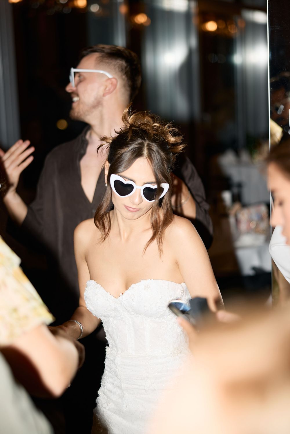 Wedding celebration on dance floor with white sunglasses and strapless dress creating festive atmosphere.