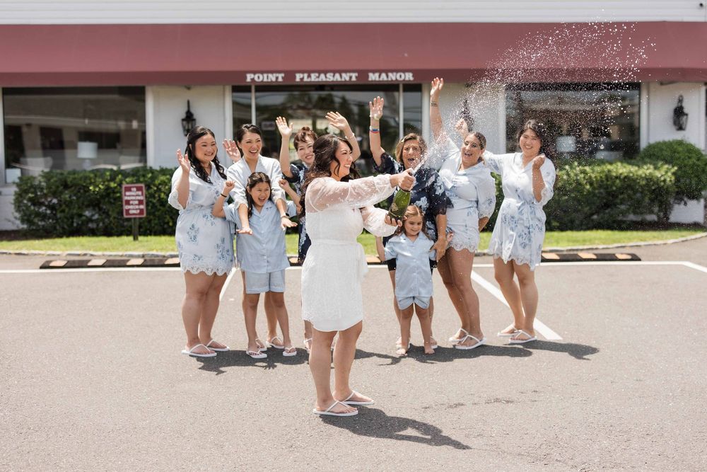 A group in coordinating light blue and white outfits celebrates joyfully outside a storefront on a sunny day.