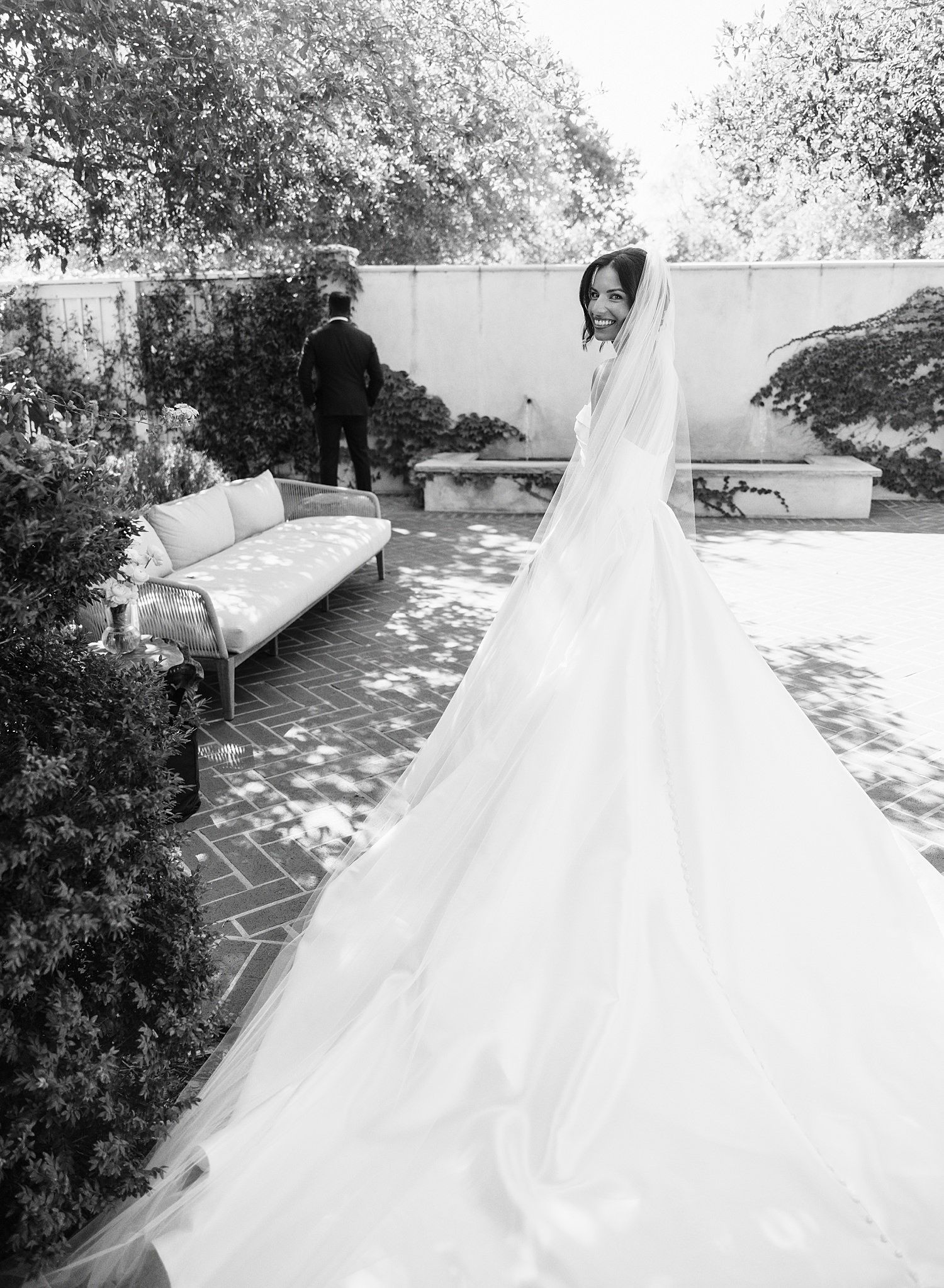 Black and white photo series showing a flowing white wedding gown with intricate details captured from multiple angles outdoors.