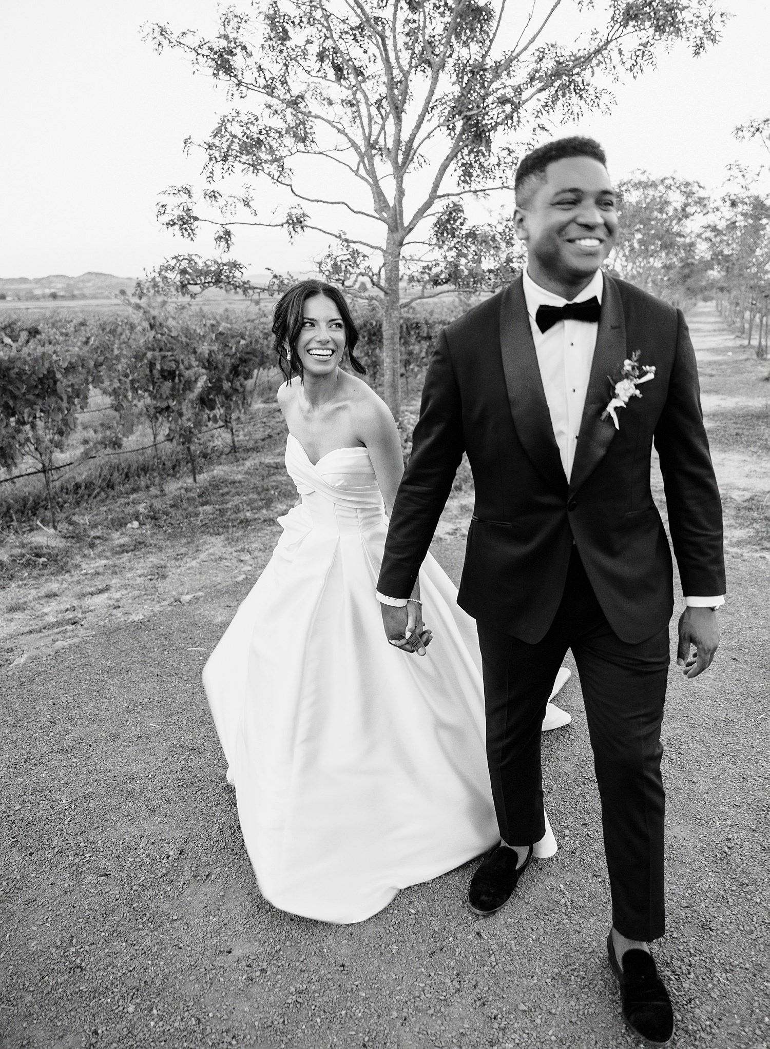 Black and white wedding photo series showing a couple walking and laughing together outdoors in formal attire.
