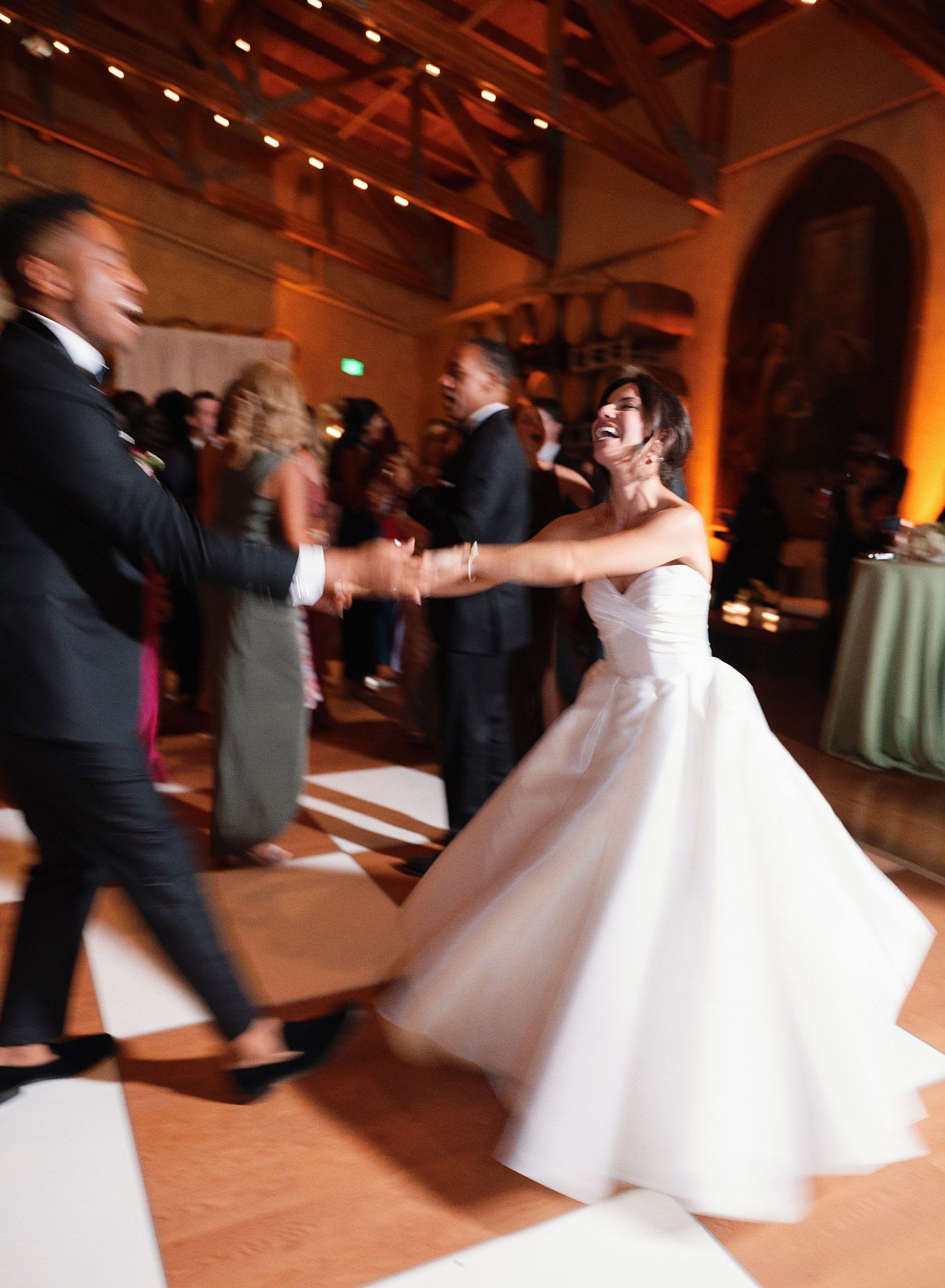 A sequence of wedding dance photos shows a couple twirling and spinning on a warmly lit ballroom floor during their first dance.