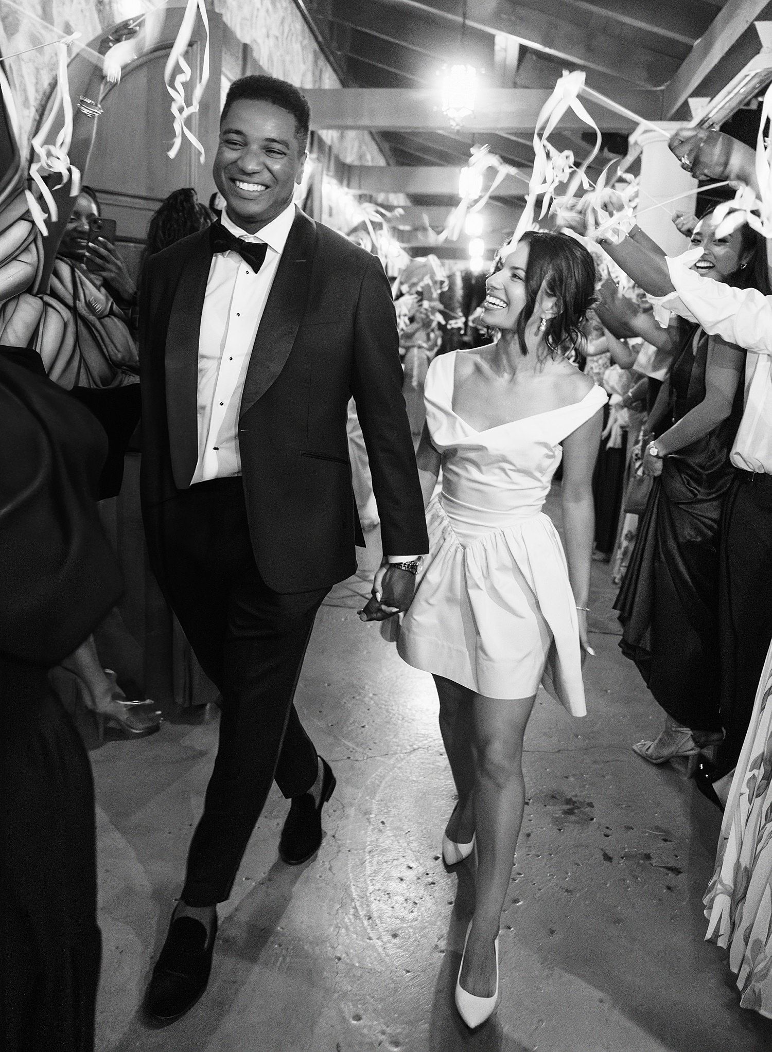 A couple in formal attire dances joyfully at a wedding reception while guests wave white napkins in celebration.