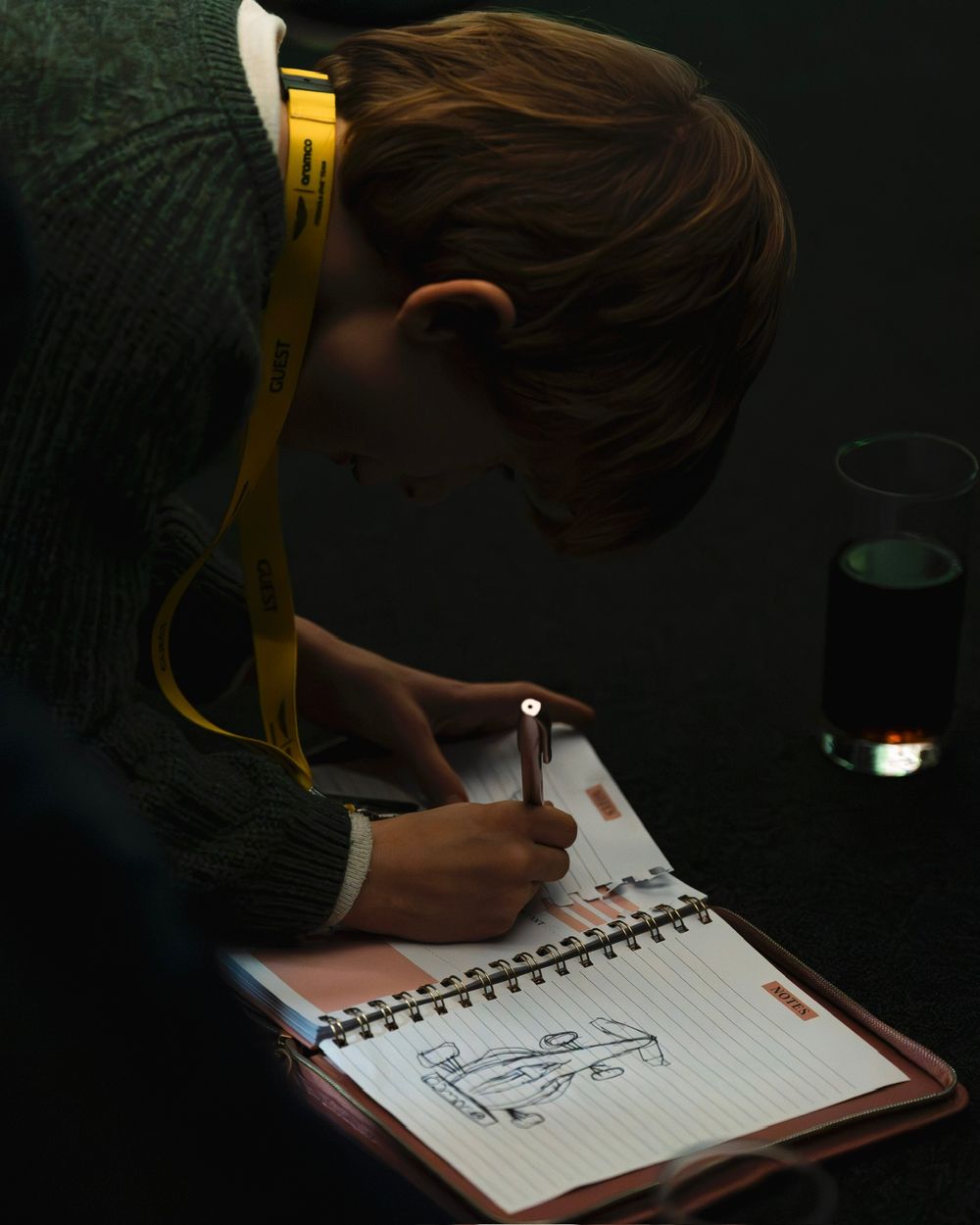 Someone sketches in a notebook under dim lighting, creating a sequence of simple drawings across multiple frames.