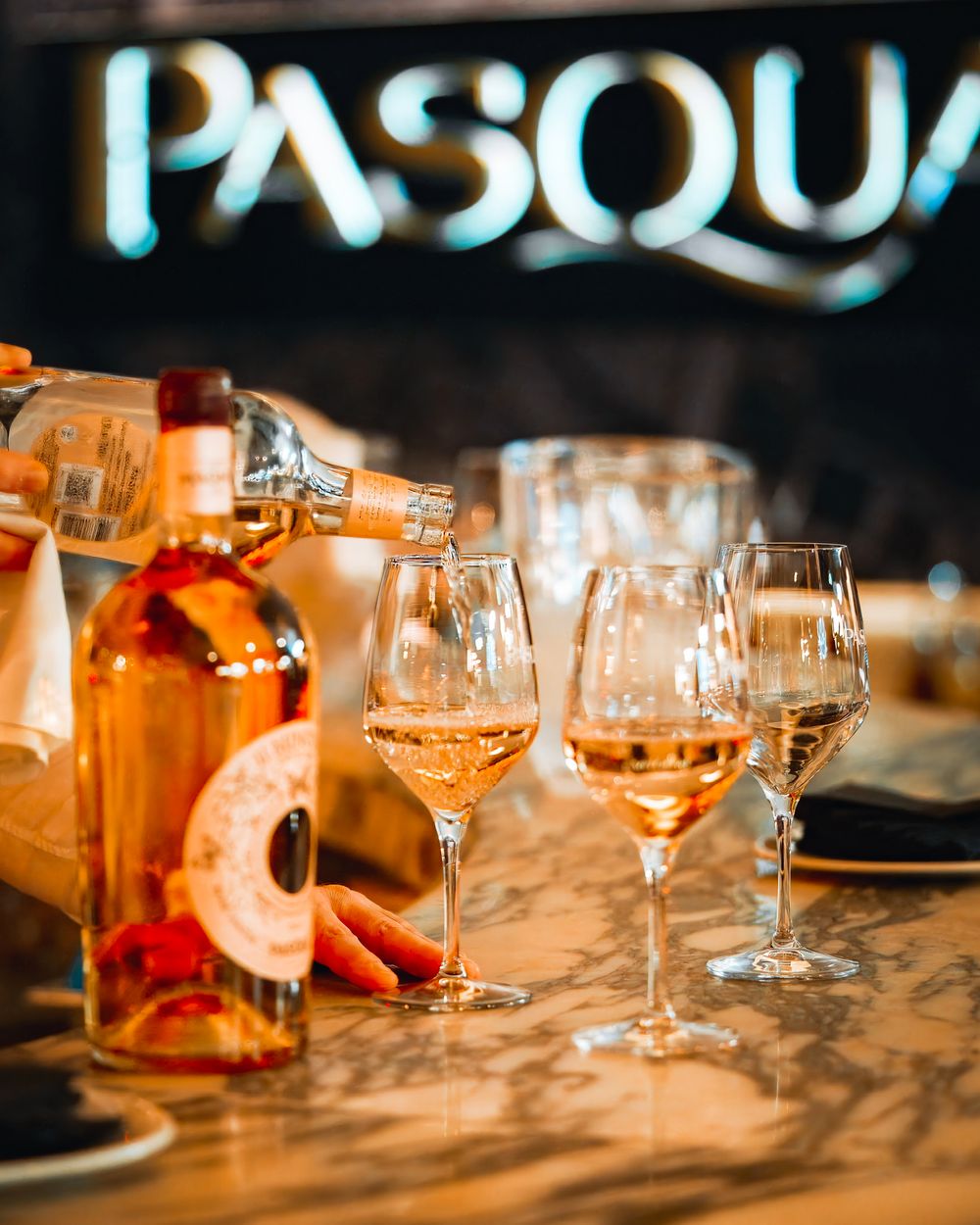 Wine glasses and bottles arranged on an elegant table setting with warm ambient lighting.