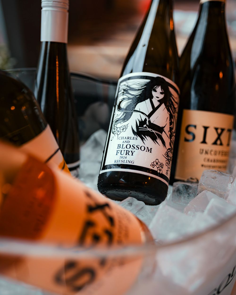 Wine bottles chilling in ice with black and white labels visible.