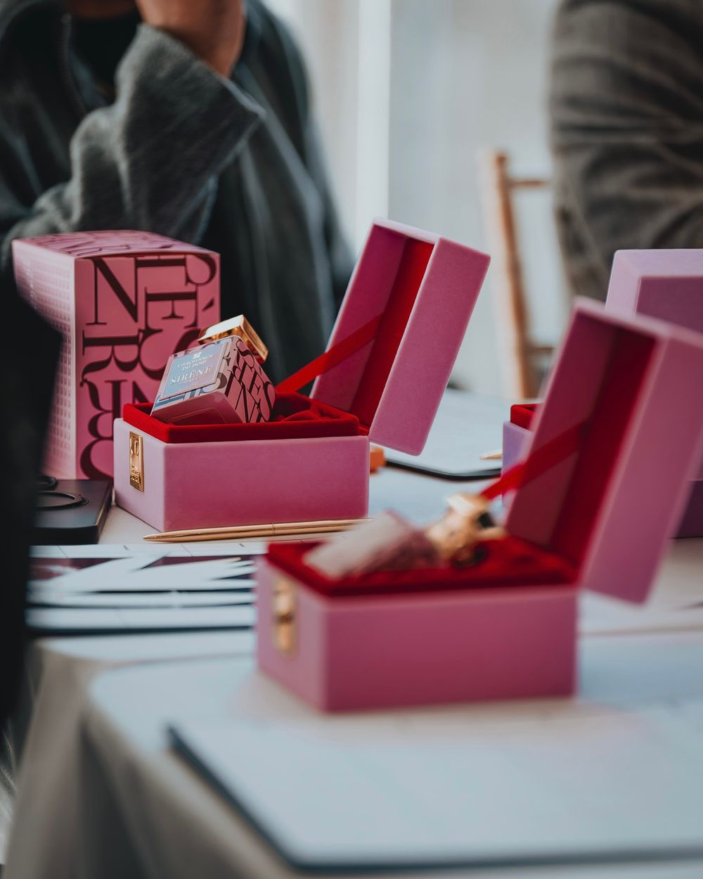 Pink gift boxes arranged on a white table during an event or presentation.