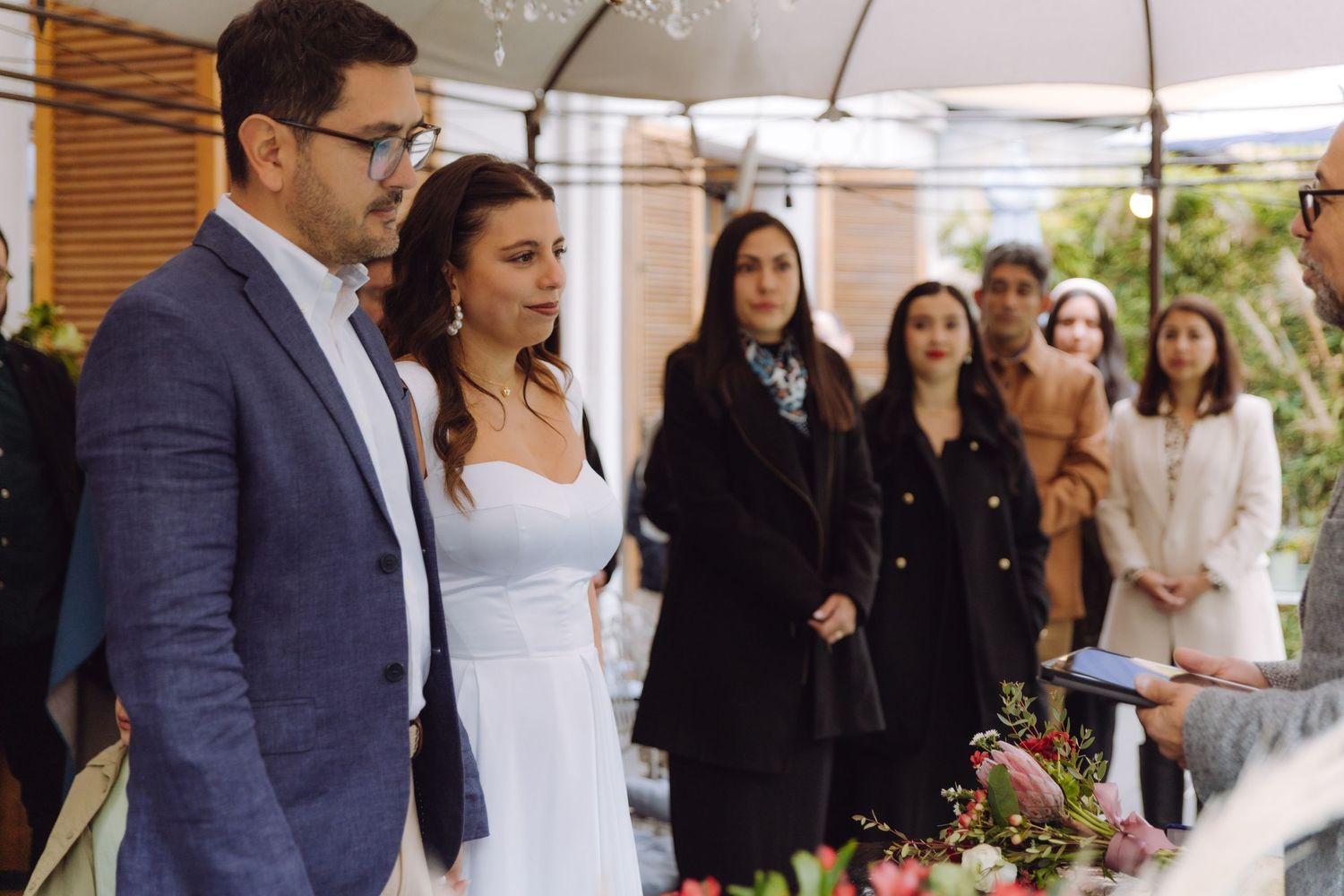 Bride and groom standing at outdoor wedding ceremony altar with guests gathered behind them.