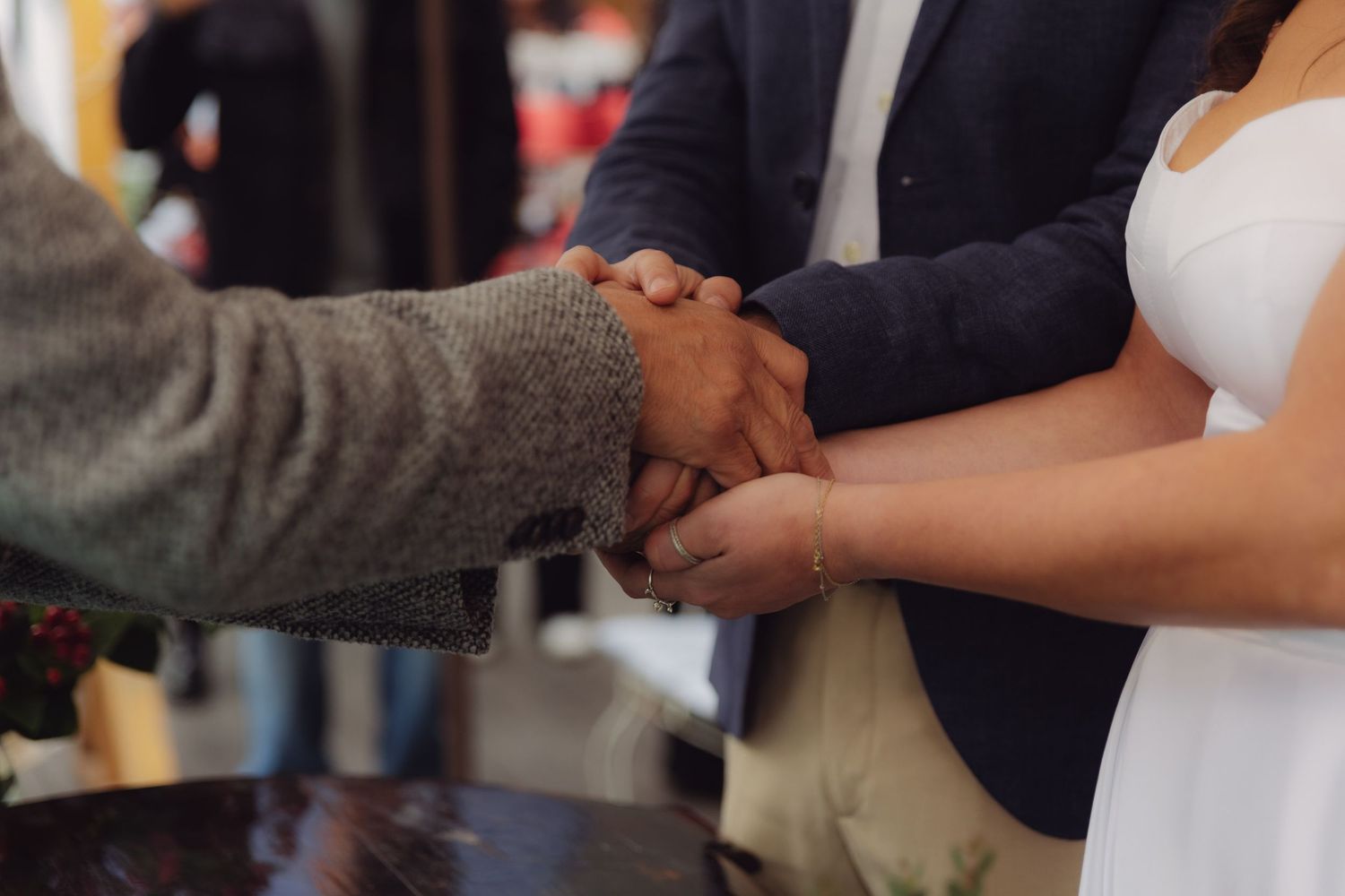 Close-up of officiant clasping joined hands of bride and groom during wedding ceremony.