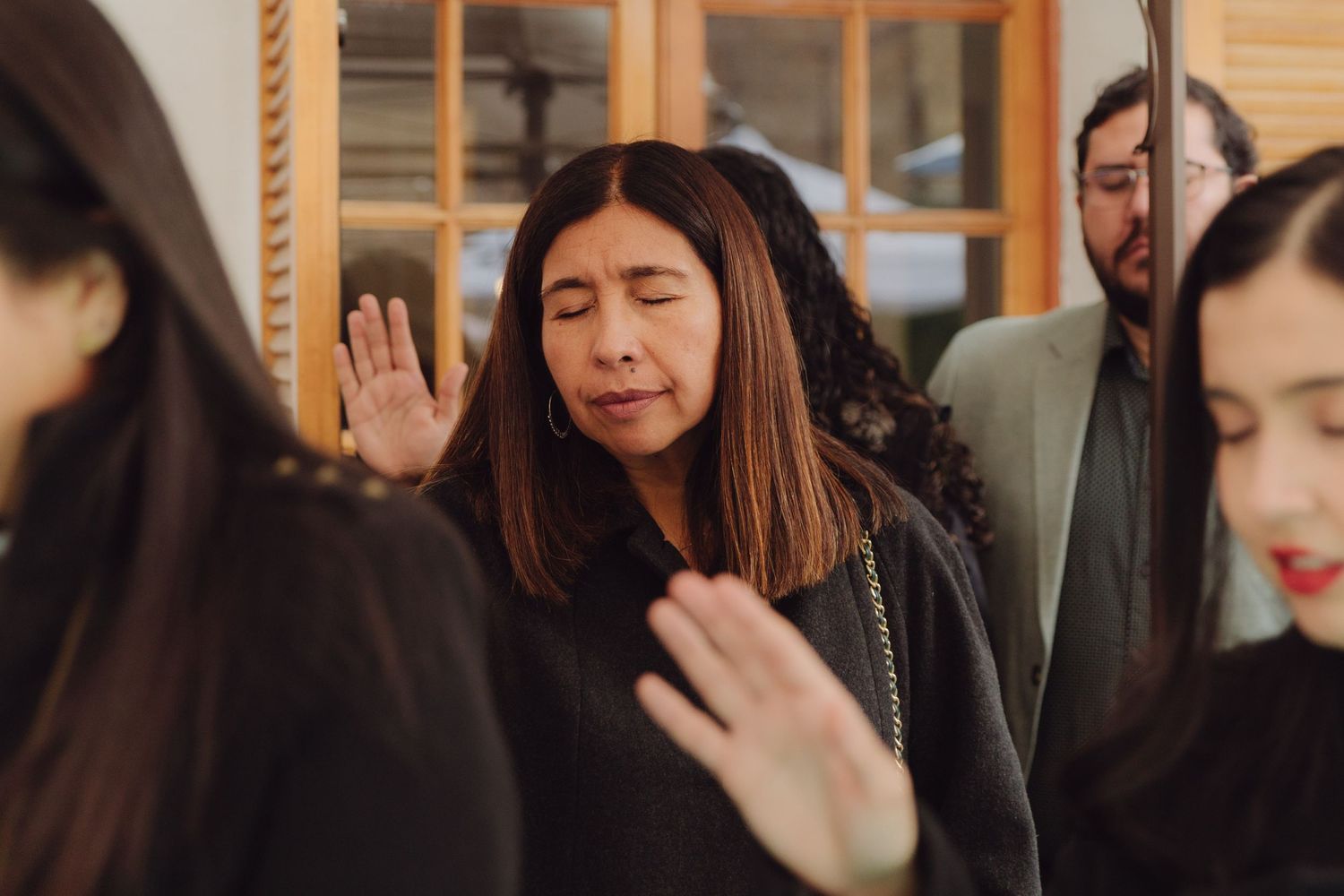 Emotional wedding guest with raised hand during a heartfelt ceremony blessing.