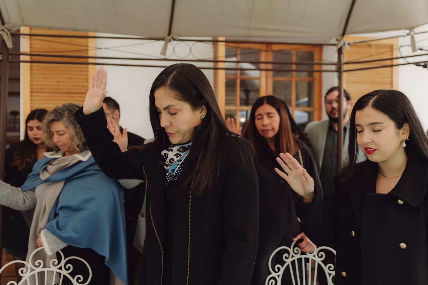 Wedding guests raising hands in blessing during an elegant outdoor ceremony.