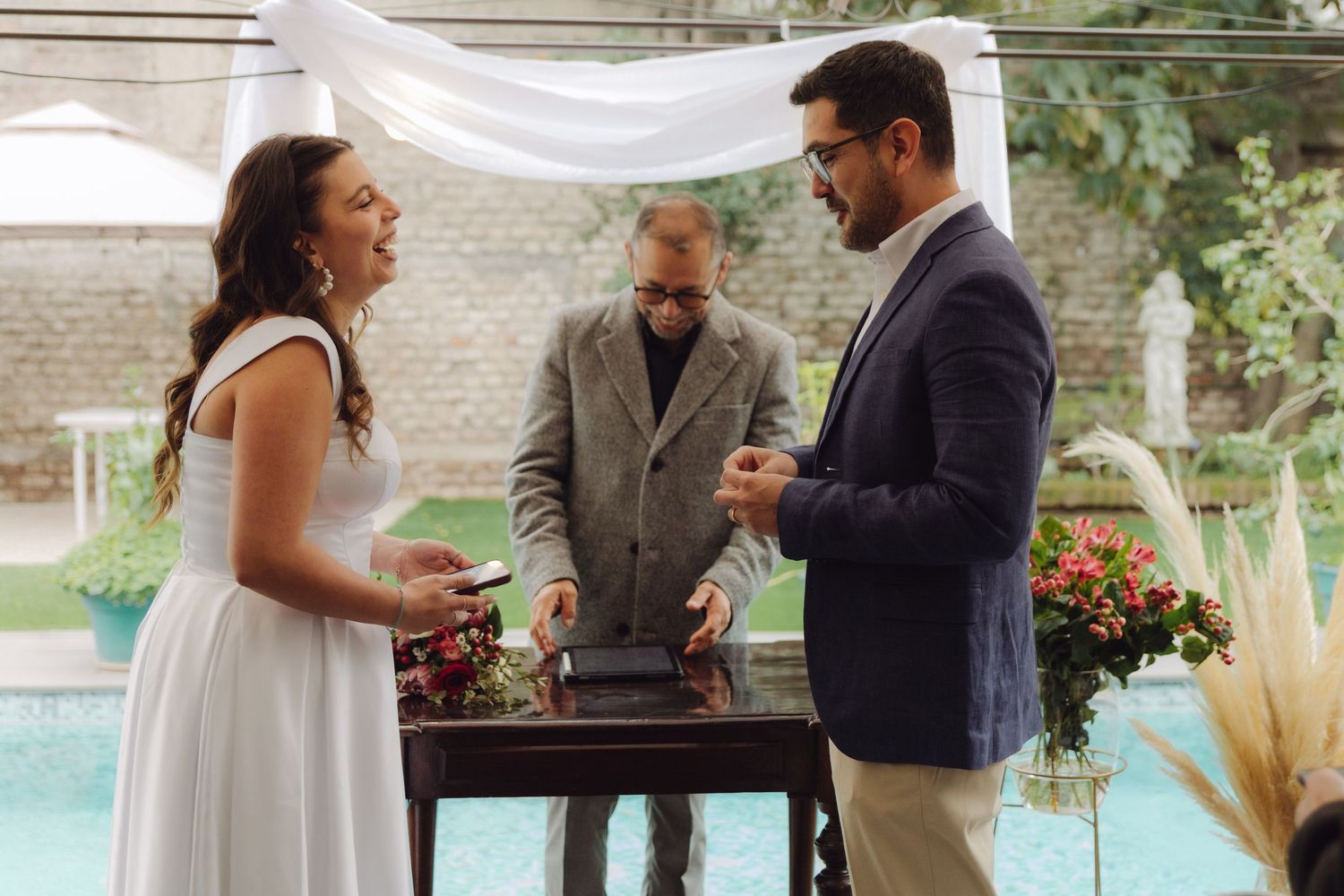 Bride and groom exchanging vows with officiant at outdoor poolside wedding.