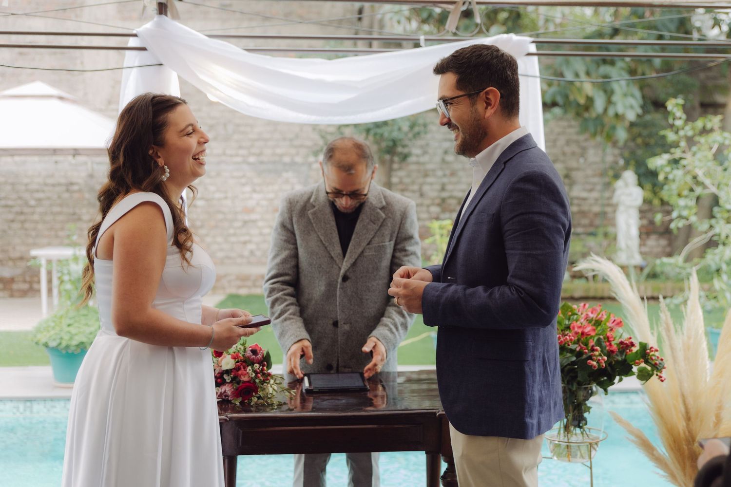 Smiling bride and groom exchanging rings at a beautiful outdoor wedding.