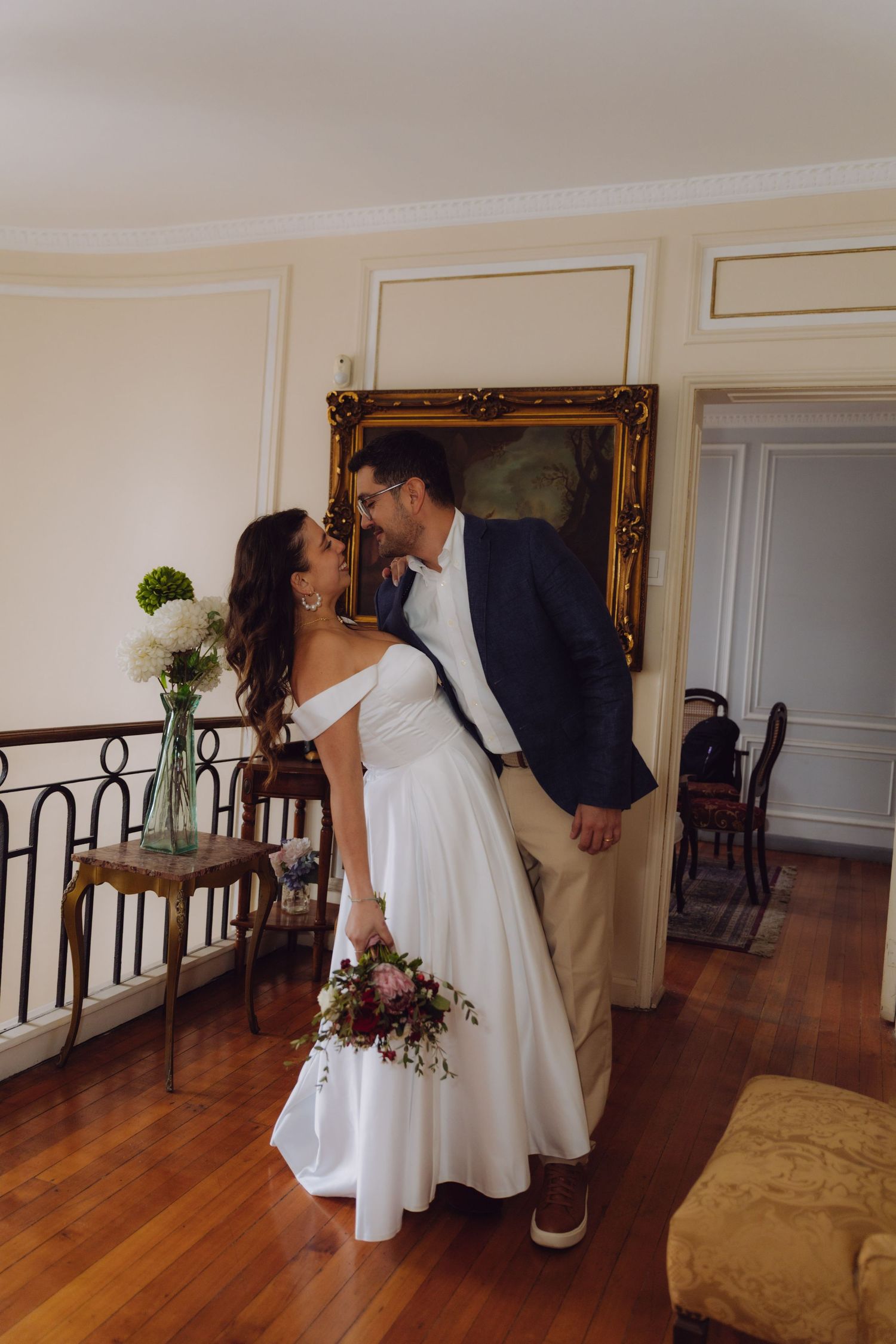 Bride and groom share a nearly kiss near golden framed portrait in elegant vintage-styled room.