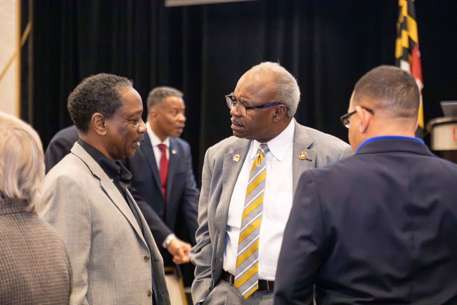 Business professionals in suits gather at a formal event, networking and engaging in conversation.