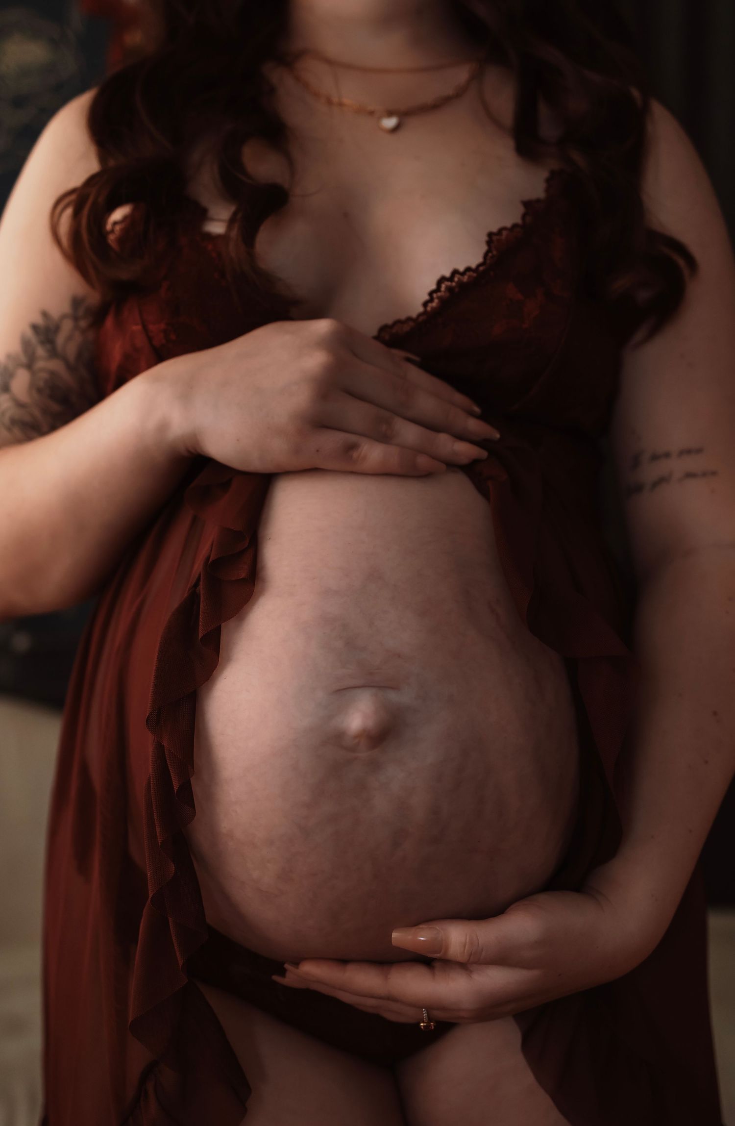 close up maternity boudoir image focusing on hands resting on a pregnant belly in soft lighting