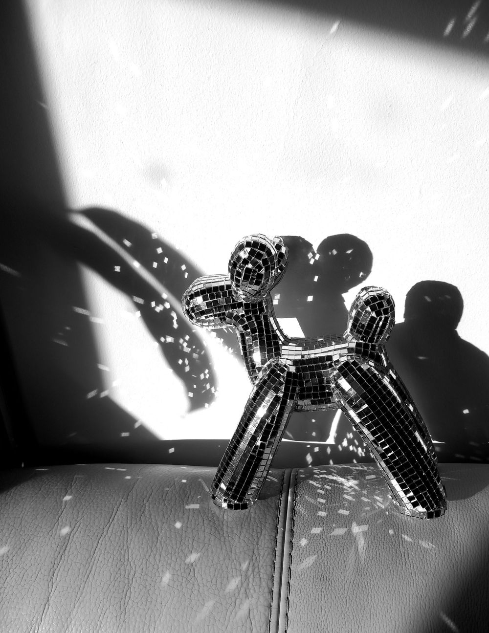 Progressive frames of a spinning disco ball casting dramatic light patterns and shadows on a surface.