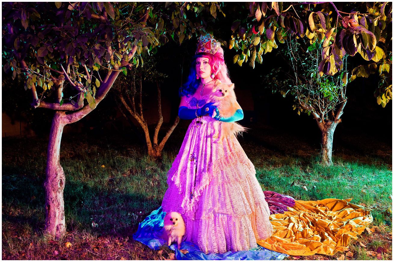 A pink and floral dress illuminated against a dark garden setting with trees and dramatic lighting effects.