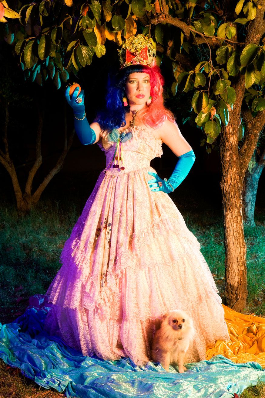 A magical nighttime photo series featuring a flowing pink ballgown dress illuminated against trees with blue lighting effects.